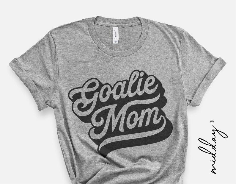 May include: Gray t-shirt with the text "Goalie Mom" in a retro, black, stylized font.