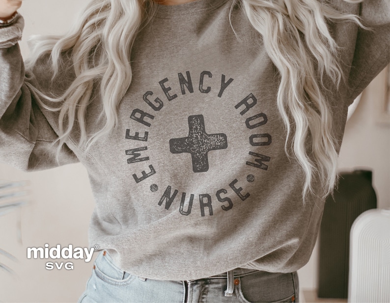 Peut inclure: Un sweat-shirt gris avec le texte "Emergency Room Nurse" dans un cercle avec un signe plus noir au centre. Le texte est dans une police de caract&egrave;res us&eacute;e.
