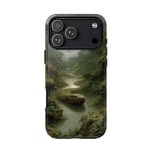 May include: A smartphone case featuring a detailed graphic print of a large, textured green snake partially submerged in a winding river within a dense, misty forest landscape. The case has a black camera module cutout with three circular lenses.