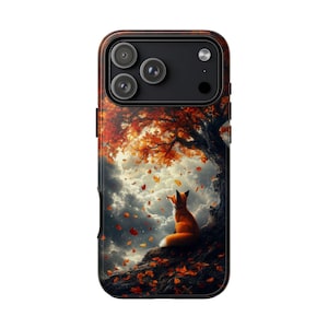 May include: A smartphone case featuring a printed illustration of a small orange fox sitting on a dark, textured tree trunk. Above the fox, a large tree with vibrant orange and red autumn leaves stretches across a cloudy, grey sky.
