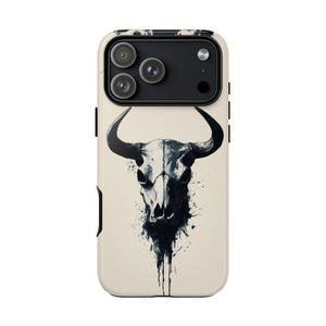 Puede incluir: Funda de teléfono con una ilustración en blanco y negro de una calavera de toro. La calavera está centrada sobre un fondo crema, con detalles de salpicaduras de tinta. Módulo de cámara negro.