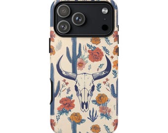 May include: A smartphone case featuring a cream-colored background with a repeating pattern of dark blue bull skulls, tall blue cacti, and vibrant orange and red flowers. The case has a black camera module cutout at the top with three lenses.