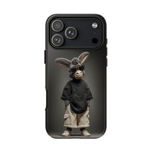 May include: Black phone case with a cartoon donkey wearing sunglasses, a black top, and beige shorts. The donkey is set against a dark grey backdrop. The phone case has a black edge and a triple-lens camera.