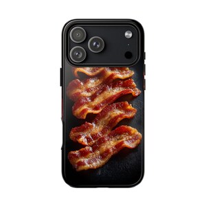 Könnte beinhalten: Schwarze Handyhülle mit einer Nahaufnahme von gebratenen Speckstreifen. Der Speck ist eine Mischung aus Rot und Braun mit knusprigen Rändern. Die Handyhülle hat einen schwarzen Rahmen und ein Kameramodul.