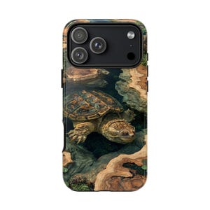 Könnte beinhalten: Eine rechteckige Smartphone-Hülle mit einer hochauflösenden Grafik einer Schnappschildkröte, die durch dunkles Wasser schwimmt, umgeben von hellen Holzmaserungstexturen. Die Hülle hat einen schwarzen Kameraausschnitt für drei Linsen.
