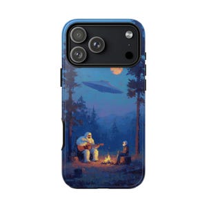 Puede incluir: Funda de teléfono azul con una ilustración fantástica de un Bigfoot tocando la guitarra junto a una fogata con una persona con traje espacial. Un OVNI sobrevuela el cielo nocturno sobre un bosque y una luna llena. La funda tiene un borde azul y un recorte para la cámara.