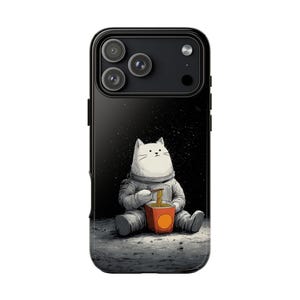 May include: Black phone case featuring a white cat astronaut seated on a lunar surface, eating noodles from a red container. The background depicts a starry night sky. The phone case has a glossy finish.