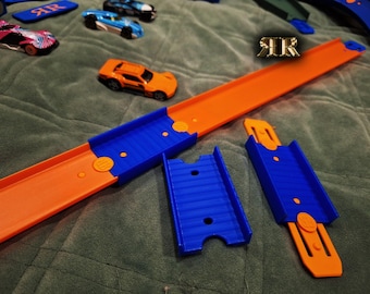 May include: Orange and blue plastic track pieces for a toy car racing set. The track pieces are designed to connect together to create a race track. The track pieces are made of durable plastic and are designed to withstand repeated use.