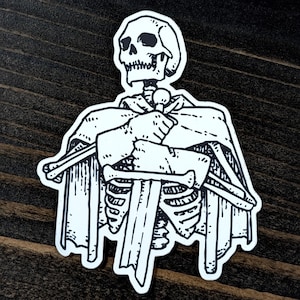 May include: A black and white sticker featuring a skeleton figure holding a sword. The skeleton is wearing a cape and has a detailed skull. The sticker is on a dark wood surface.