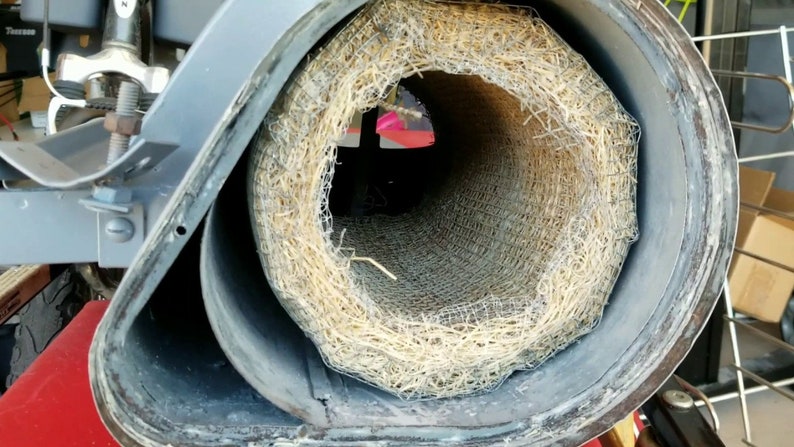 Op de afbeelding: Close-up van een ronde, grijze metalen buis met een stroomachtig materiaal eromheen gewikkeld. Het stroomachtige materiaal wordt op zijn plaats gehouden door een draadgaas.