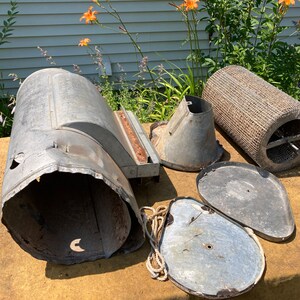 Op de afbeelding: Een set vintage metalen onderdelen voor een vogelvoeder. De set bevat een grote cilindrische basis, een trechter, twee deksels en een draadgaascilinder.