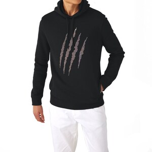 May include: Black hooded sweatshirt with a claw mark design on the front. The claw marks are made of a lighter color, possibly silver or gray, and are vertically oriented. The sweatshirt has a front pocket and long sleeves.