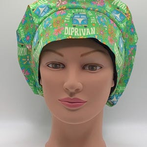 May include: Green scrub cap featuring a repeating pattern of blue vans, flowers, and the text "TAKE A RIDE ON THE DIPRIVAN". This cap is designed to cover the head and hair, and is likely for medical or professional use.