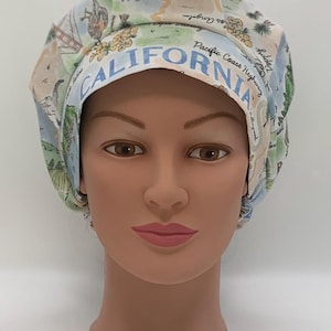 Peut inclure: Un bonnet de travail blanc avec un motif de carte de Californie bleu et vert. Le bonnet porte l'inscription "CALIFORNIA" en bleu sur le devant.