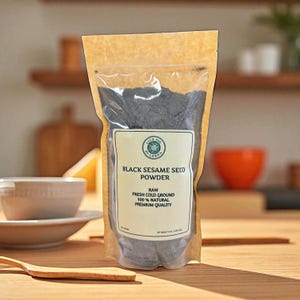 Może przedstawiać: Przezroczysta torebka wypełniona czarnym proszkiem z nasion sezamu. Torebka ma brązowe papierowe tło i białą etykietę z napisem "Black Sesame Seed Powder". Etykieta zawiera r&oacute;wnież napis "Raw, Fresh Cold Ground, 100% Natural, Premium Quality".