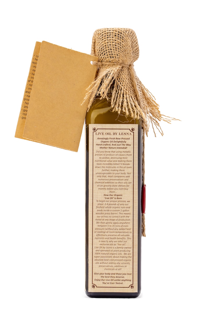 May include: A brown glass bottle with a hessian lid, filled with a golden liquid. The bottle label reads "Live Oil by Lesna" and describes the oil as "Amazingly Fresh Raw-Pressed Organic Oil Delightfully Hand-crafted, And Just The Way Mother Nature Intended!"