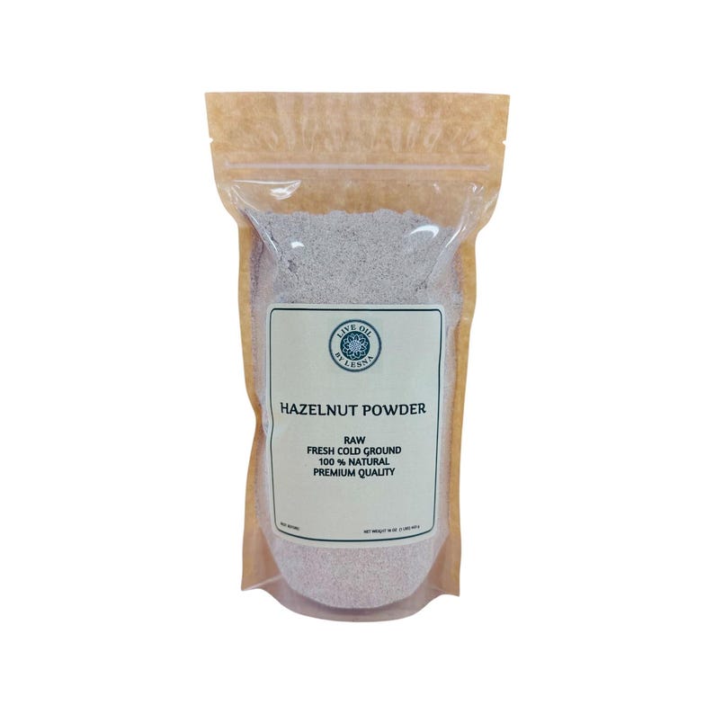 May include: A stand-up pouch containing light brown hazelnut powder. The label features the text LIVE OIL BY LESNA, HAZELNUT POWDER, RAW, FRESH COLD GROUND, 100% NATURAL, PREMIUM QUALITY, and NET WEIGHT 16 OZ (1 LB/454 G).