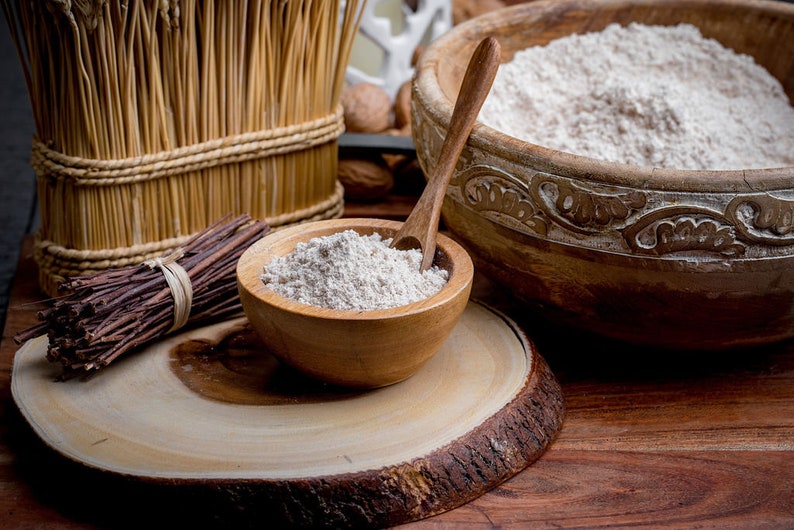 Peut inclure: Gros plan sur deux bols en bois remplis de farine blanche. Les bols sont sur une surface en bois avec un morceau d'&eacute;corce de bois au premier plan.