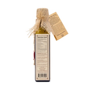 May include: A glass bottle of organic poppy seed oil with a burlap-wrapped top. The bottle label includes nutrition facts, ingredients, and the text "Proudly made in the USA". The label also includes a certification seal for organic products.