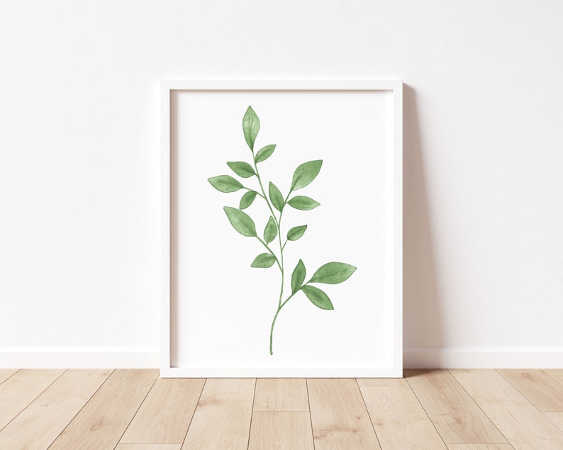 May include: A white framed print of a watercolor painting of a green leafy branch with a white background.