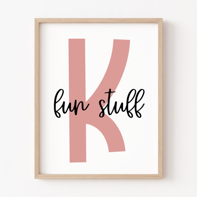 May include: A framed print featuring a pink letter K and the text "fun stuff" in black cursive writing.