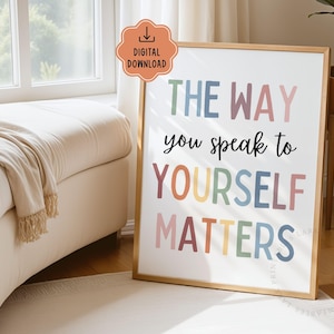 Puede incluir: Un cartel enmarcado con el texto "THE WAY you speak to YOURSELF MATTERS" en letras de colores. El cartel tiene un marco dorado y se exhibe en una habitaci&oacute;n luminosa con una ventana y un sof&aacute; beige.