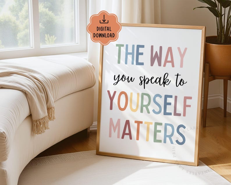 Puede incluir: Un cartel enmarcado con el texto "THE WAY you speak to YOURSELF MATTERS" en letras de colores. El cartel tiene un marco dorado y se exhibe en una habitaci&oacute;n luminosa con una ventana y un sof&aacute; beige.