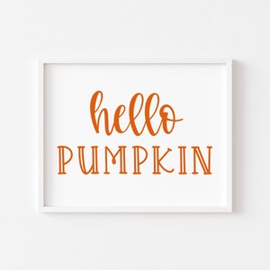 May include: A white framed print with the text "hello pumpkin" in orange lettering.