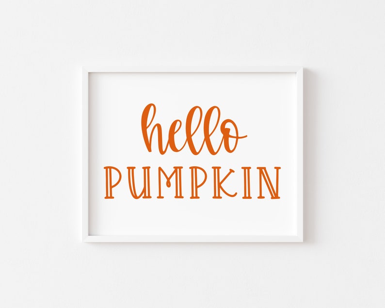 May include: A white framed print with the text "hello pumpkin" in orange lettering.