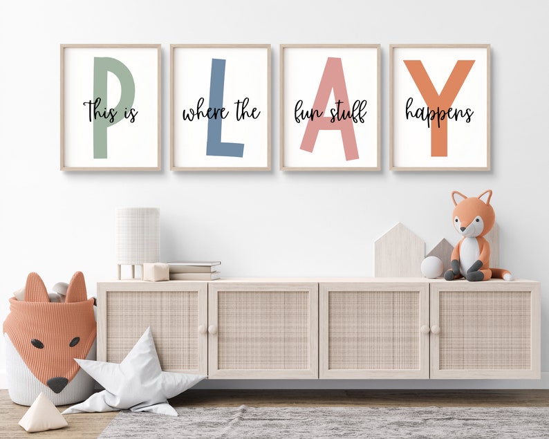 May include: Four framed prints with the word "PLAY" spelled out in large, colorful letters. Each letter is a different color: green, blue, pink, and orange. The text "This is where the fun stuff happens" is written in black cursive below the letters.