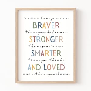 May include: A motivational quote in a white frame with a light wood border. The quote reads "remember you are BRAVER than you believe STRONGER than you seem SMARTER than you think AND LOVED more than you know". The words are in different colors, including blue, green, yellow, orange, and red.