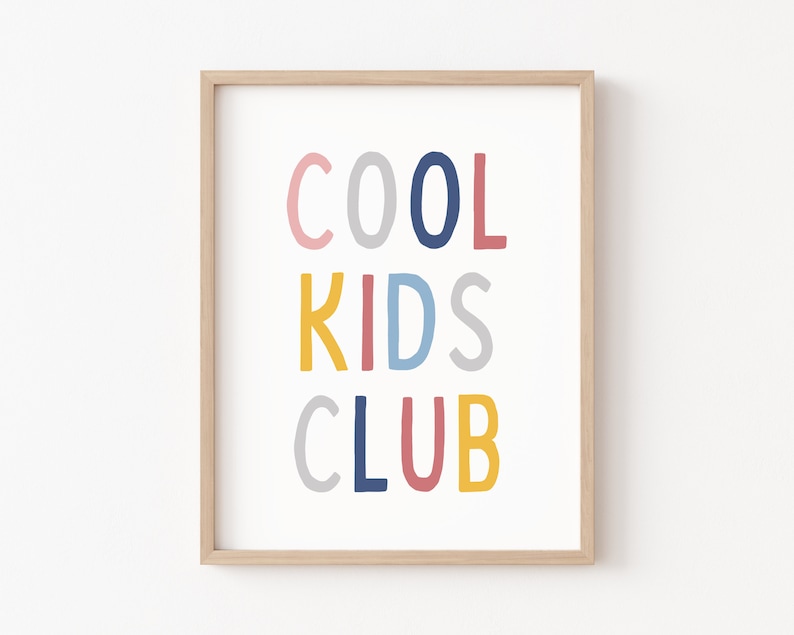 May include: A framed print with the text "COOL KIDS CLUB" in colorful, handwritten letters. The letters are in shades of pink, blue, yellow, and gray.