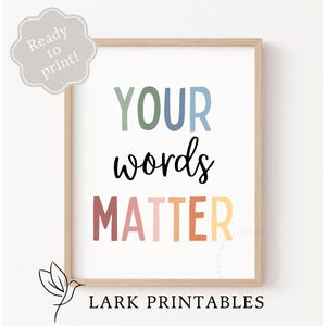 Op de afbeelding: Printbare wandkunst met de tekst "YOUR words MATTER" in regenboogkleuren. De tekst is in een speels, handgeschreven lettertype. De print is klaar om in te lijsten.