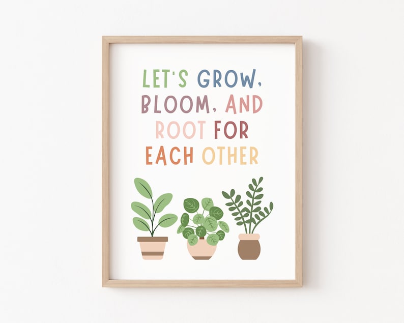 Op de afbeelding: Een ingelijst print met de tekst "Let's Grow, Bloom, and Root for Each Other" in kleurrijke letters. De print toont drie potplanten met groene bladeren.