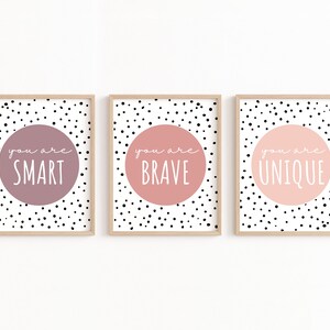 May include: Three framed prints with a white background and black polka dots. Each print features a large pink or purple circle with white text that reads "You are SMART", "You are BRAVE", and "You are UNIQUE".