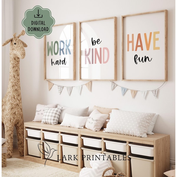 Może przedstawiać: Trzy oprawione wydruki z napisami „WORK hard”, „be KIND” i „HAVE fun” w kolorowych literach. Poniżej znajduje się drewniana szafka do przechowywania z białymi pojemnikami. Dekoracyjna żyrafa i poduszki dopełniają wystroju pokoju.