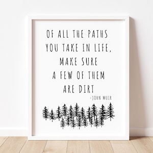 May include: Black and white typography print with a quote by John Muir: "Of all the paths you take in life, make sure a few of them are dirt." The quote is surrounded by a silhouette of a forest.