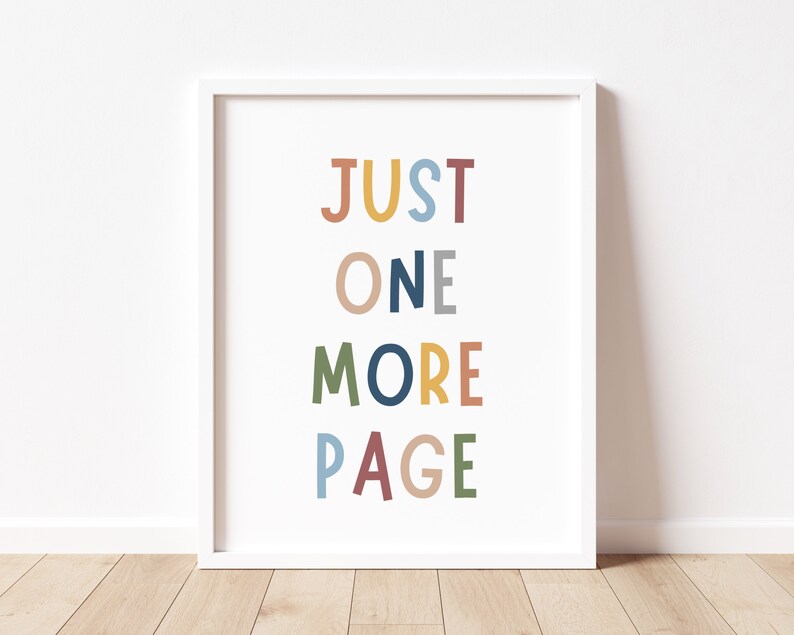 May include: A white framed print with the text "JUST ONE MORE PAGE" in colorful letters. The letters are in different colors, including yellow, orange, red, blue, green, and gray.