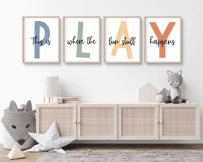 May include: Four framed prints with the word "PLAY" spelled out in large, colorful letters. Each letter is a different color: blue, green, yellow, and orange. The text "This is where the fun stuff happens" is written in black below the letters.