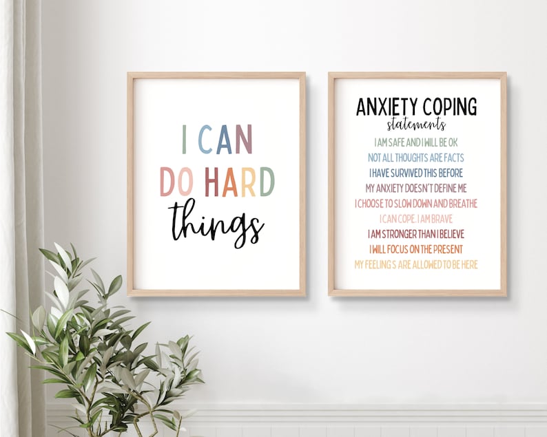 Puede incluir: Dos l&aacute;minas enmarcadas con citas inspiradoras. Una dice "I CAN DO HARD things" en letras coloridas. La otra enumera "ANXIETY COPING statements" con afirmaciones. Ambas est&aacute;n en marcos de madera clara.