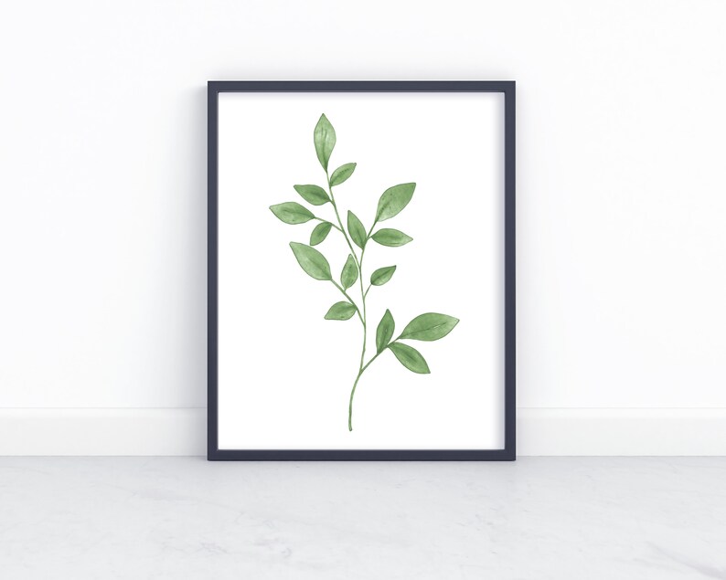 May include: A black framed print with a watercolor illustration of a green leafy branch on a white background.