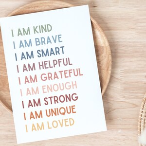 K&ouml;nnte beinhalten: Eine wei&szlig;e Karte mit dem Text "I AM KIND", "I AM BRAVE", "I AM SMART", "I AM HELPFUL", "I AM GRATEFUL", "I AM ENOUGH", "I AM STRONG", "I AM UNIQUE", "I AM LOVED" in verschiedenen Farben gedruckt.