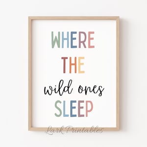 以下が含まれることがあります： 「WHERE THE wild ones SLEEP」というテキストがカラフルな文字で書かれた額装されたプリント。テキストは虹色のカラーパターンで書かれています。プリントは白い背景にあり、木製のフレームが付いています。