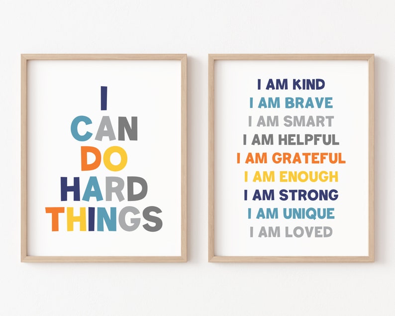 May include: Two framed prints with motivational messages. The left print has the text "I CAN DO HARD THINGS" in colorful letters. The right print has the text "I AM KIND, I AM BRAVE, I AM SMART, I AM HELPFUL, I AM GRATEFUL, I AM ENOUGH, I AM STRONG, I AM UNIQUE, I AM LOVED" in colorful letters.