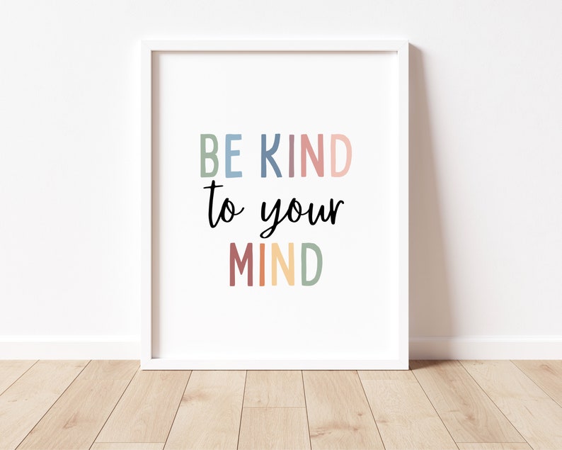 Op de afbeelding: Witte ingelijste print met de tekst "BE KIND to your MIND" in kleurrijke letters. De letters zijn in tinten blauw, roze, rood, geel en groen.