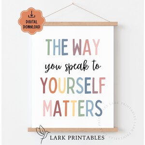 Puede incluir: Un p&oacute;ster motivacional con el texto "THE WAY you speak to YOURSELF MATTERS" en varios colores. El p&oacute;ster es una descarga digital y est&aacute; sujeto por un marco de madera. La parte inferior del p&oacute;ster tiene el texto "LARK PRINTABLES".