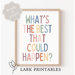 May include: A printable wall art design with the text "What's the best that could happen?" in colorful letters on a white background. The text is in a modern, playful font. The design is framed in a light wood frame. The text "Lark Printables" is printed below the design.