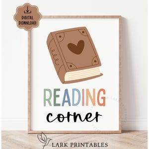 May include: A framed print with a brown book illustration and the words "READING corner" in colorful text. The book has a heart on the cover. A digital download icon is in the upper left corner.