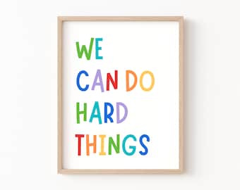 May include: A framed print with the text "WE CAN DO HARD THINGS" in rainbow colors. The letters are in a playful, hand-drawn style.