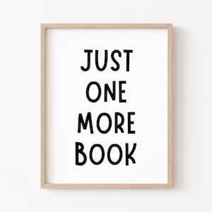 May include: A framed print with the text "JUST ONE MORE BOOK" in black bold letters on a white background.